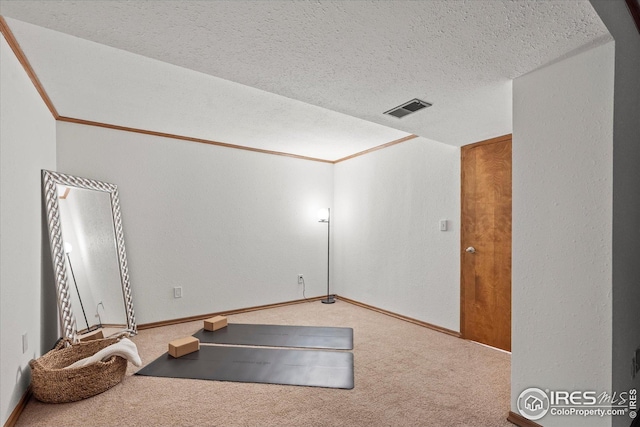 exercise area featuring carpet, visible vents, baseboards, and a textured ceiling