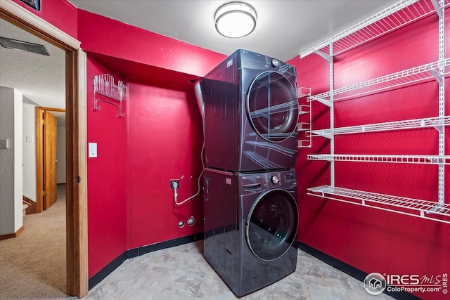 laundry room featuring stacked washer / dryer, visible vents, laundry area, and baseboards