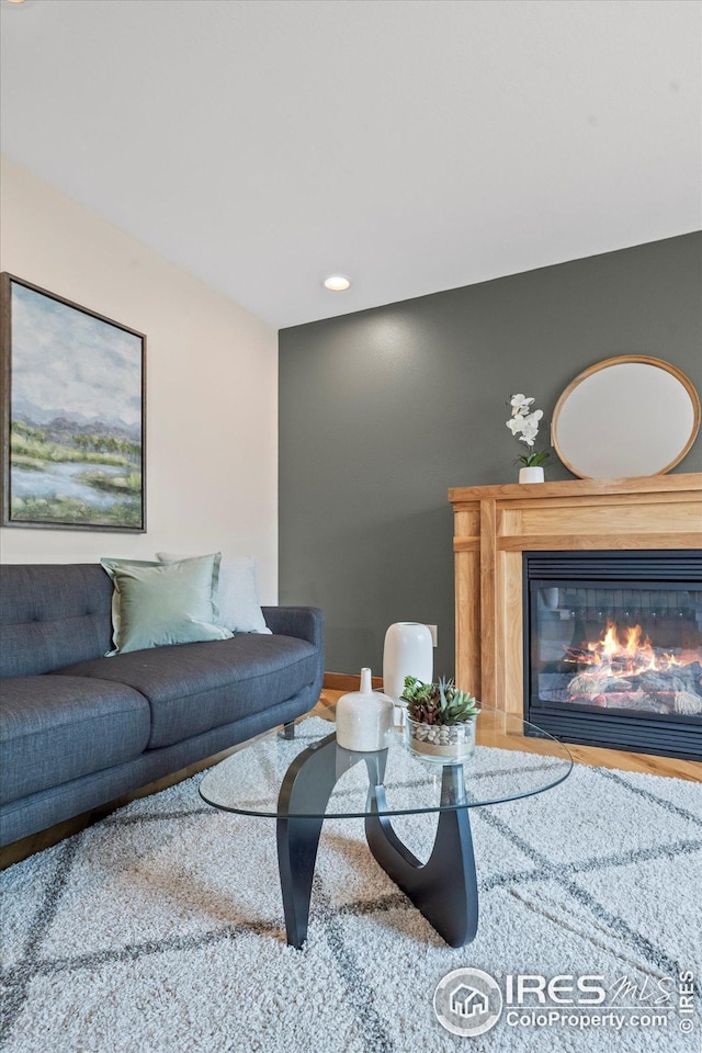 living area with a glass covered fireplace, wood finished floors, and recessed lighting