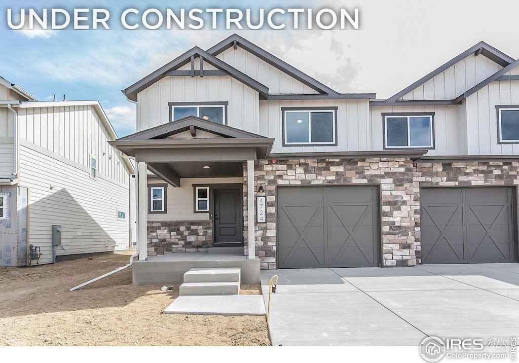 view of front of house with board and batten siding, an attached garage, driveway, and stone siding