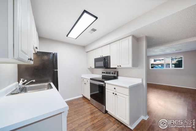 kitchen featuring white cabinets, a sink, light countertops, black appliances, and dark wood finished floors