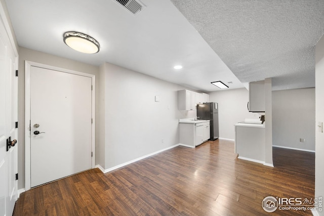 unfurnished living room with dark wood-style floors, recessed lighting, visible vents, and baseboards