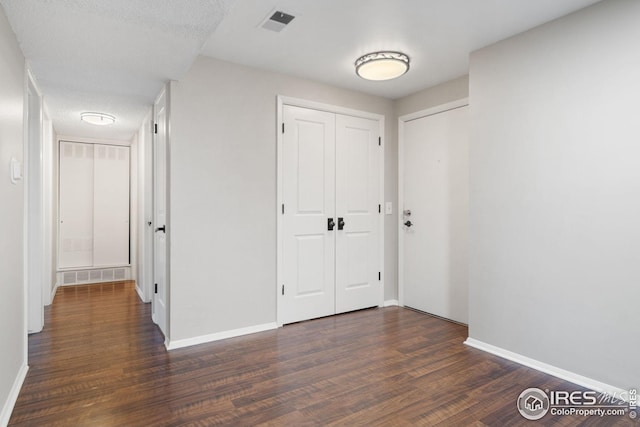 interior space with a closet, visible vents, baseboards, and dark wood-type flooring