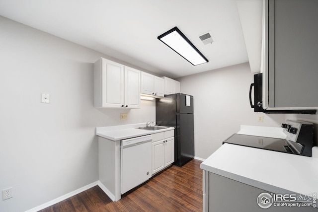 kitchen featuring dark wood-style floors, a sink, black appliances, visible vents, and baseboards