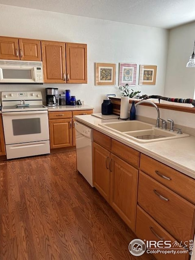 kitchen with white appliances, brown cabinets, light countertops, and a sink