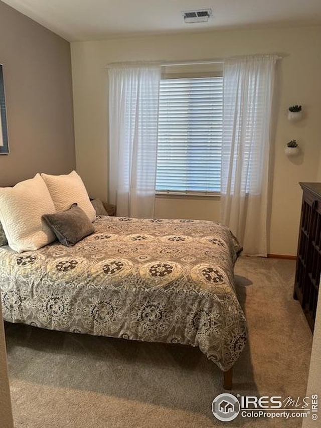 bedroom featuring visible vents and light carpet