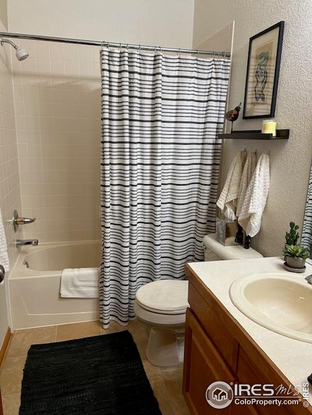 full bath featuring tile patterned flooring, shower / bath combination with curtain, toilet, a textured wall, and vanity