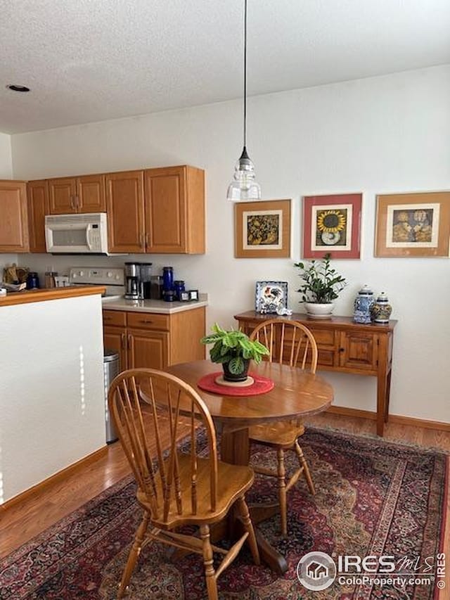 dining space featuring a textured ceiling, vaulted ceiling, and wood finished floors