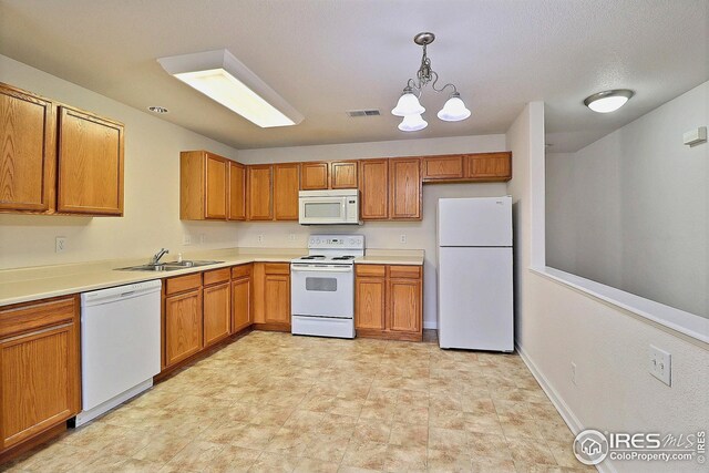 3740 Ponderosa Ct Unit 2, Evans, CO 80620 - kitchen with a sink, an inviting chandelier, white appliances, visible vents, and pendant lighting