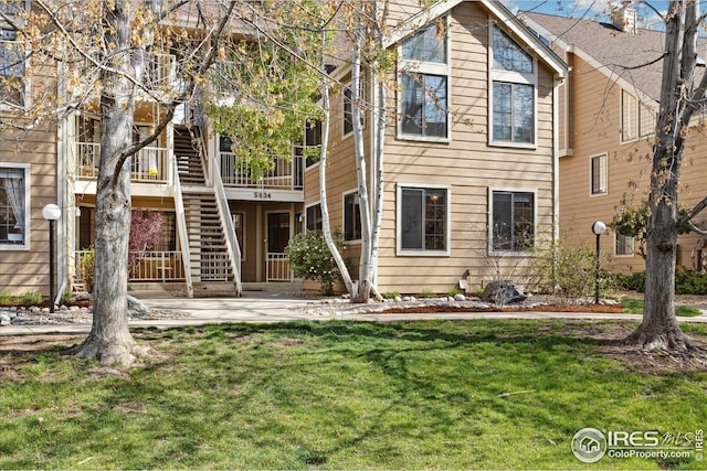 view of front of home with stairs, a front lawn, and a patio