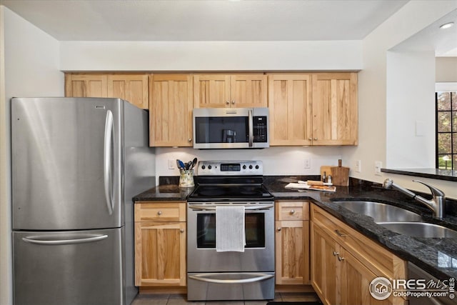 kitchen featuring a sink, dark stone counters, and stainless steel appliances