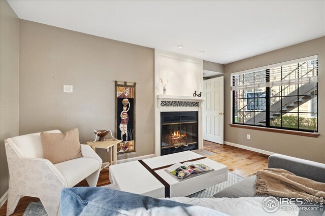 living area featuring baseboards, a fireplace with flush hearth, and light wood-style floors