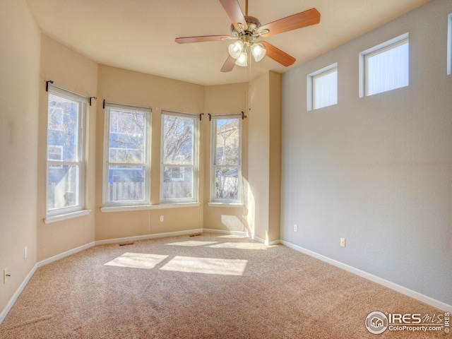 unfurnished room featuring baseboards, visible vents, ceiling fan, and carpet