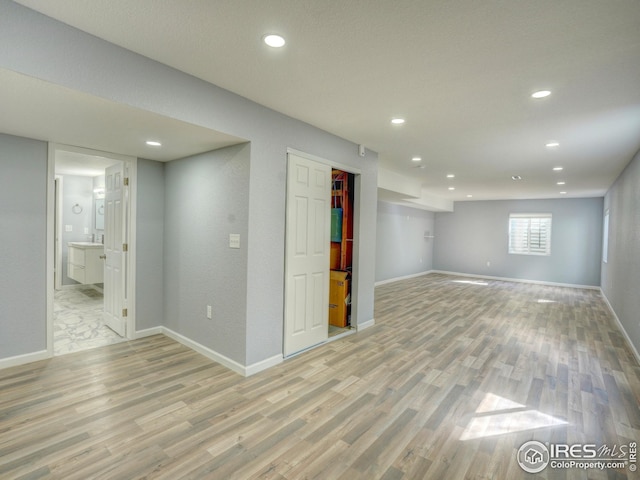 below grade area with recessed lighting, light wood-style flooring, and baseboards