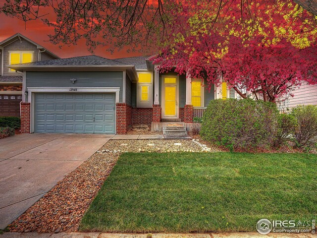 view of front facade featuring brick siding, a front lawn, driveway, and an attached garage