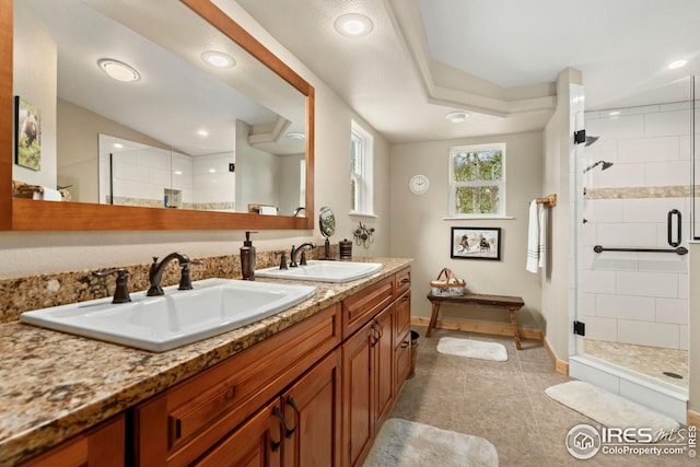 full bathroom featuring baseboards, a stall shower, double vanity, and a sink
