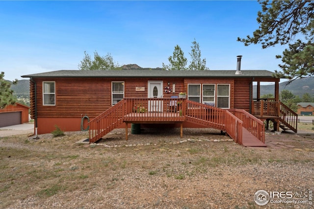 rear view of property featuring log siding, a deck, and stairs