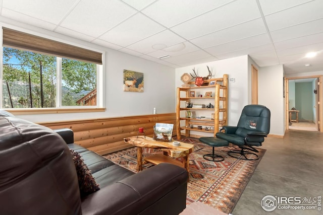 living room with finished concrete flooring and a drop ceiling