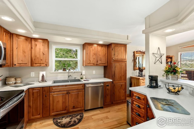kitchen with light countertops, stainless steel appliances, light wood-type flooring, and a sink
