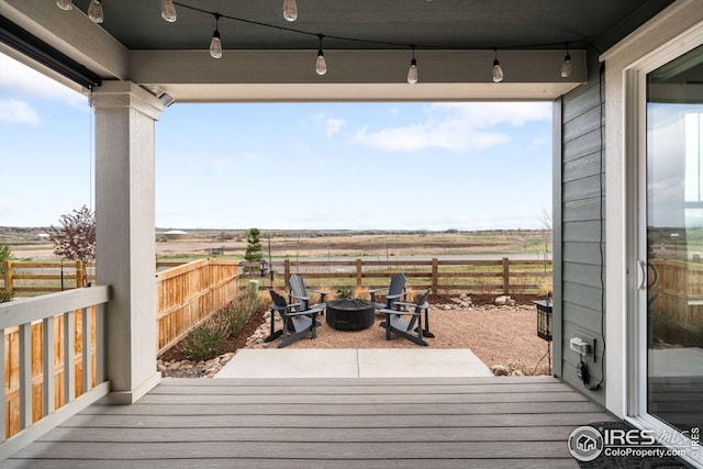 wooden deck with an outdoor fire pit, a rural view, and fence