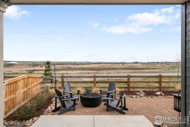 view of patio featuring a rural view, a fire pit, and a fenced backyard