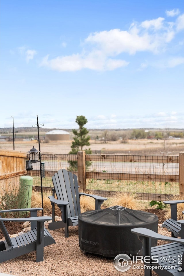 exterior space with fence, a fire pit, and a rural view
