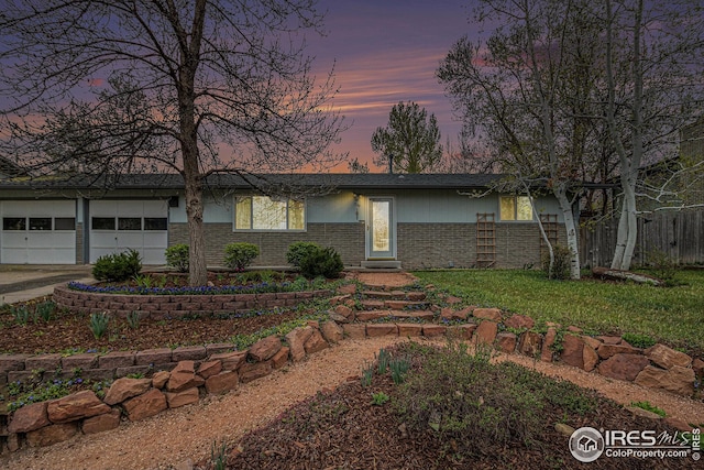 single story home with driveway, an attached garage, fence, brick siding, and a front lawn
