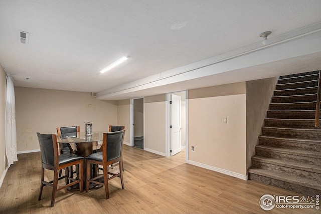 dining room with visible vents, light wood finished floors, stairs, and baseboards