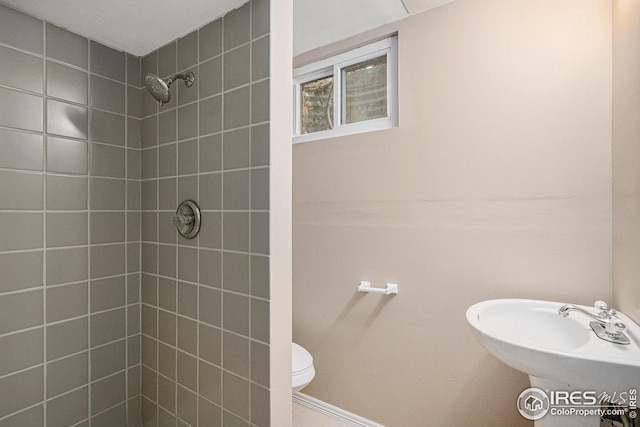 bathroom featuring toilet, a sink, and tiled shower