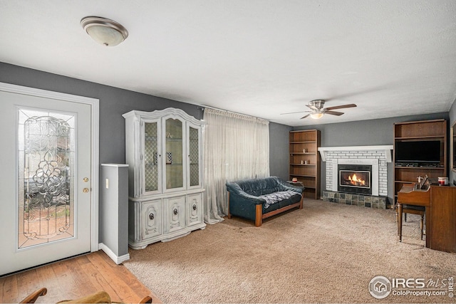 living area with baseboards, a ceiling fan, and a fireplace