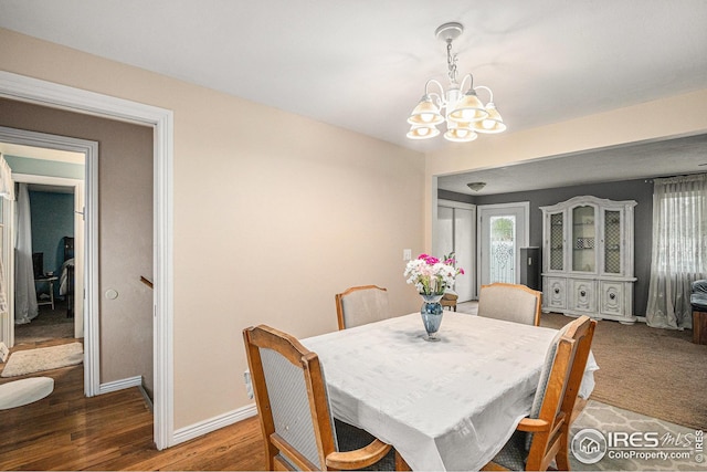 dining room featuring baseboards, wood finished floors, and an inviting chandelier
