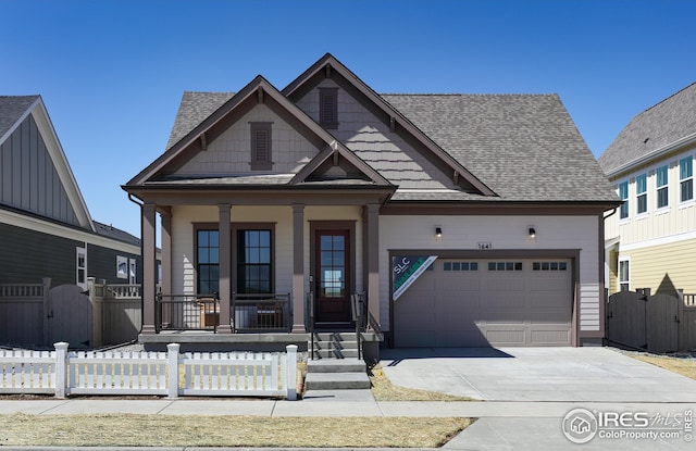 craftsman-style house with covered porch, a fenced front yard, a gate, and driveway
