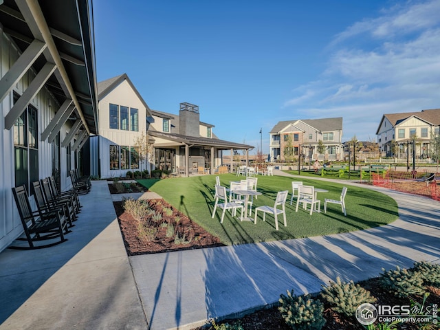 view of property's community with a lawn, a patio area, and a residential view