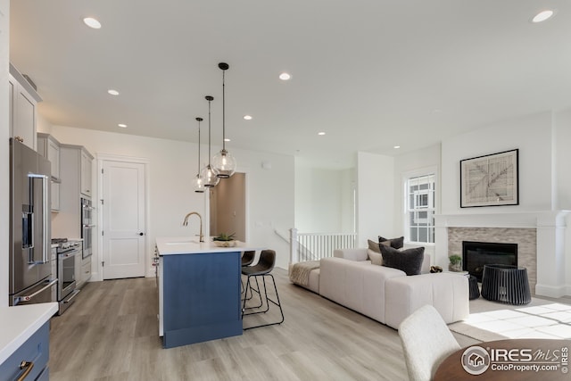 kitchen with high end appliances, a breakfast bar area, light countertops, light wood-type flooring, and open floor plan