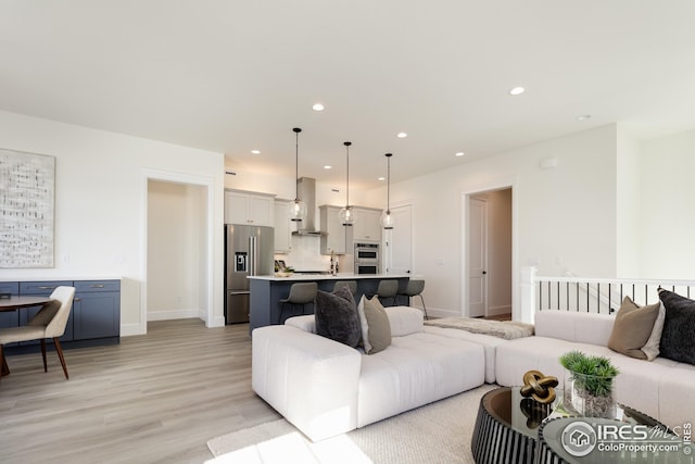 living area with recessed lighting, baseboards, and light wood-type flooring