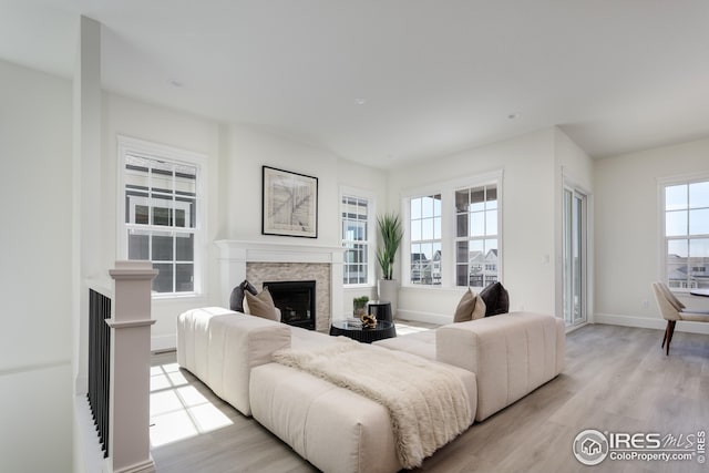 living area featuring light wood-type flooring, baseboards, and a fireplace
