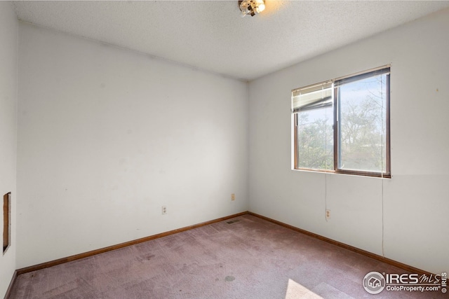 unfurnished room with carpet, a textured ceiling, and baseboards