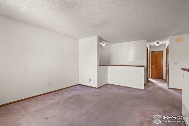 empty room featuring baseboards, a textured ceiling, and carpet