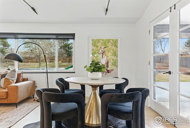 dining space with track lighting, french doors, and light wood-type flooring