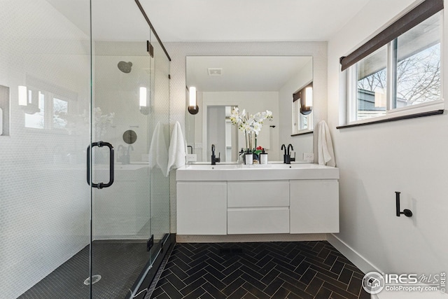 full bath featuring double vanity, a shower stall, and baseboards