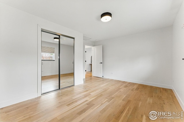 unfurnished bedroom with a closet, baseboards, and light wood-type flooring