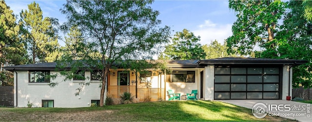 view of front of home featuring a front lawn, driveway, an attached garage, and brick siding