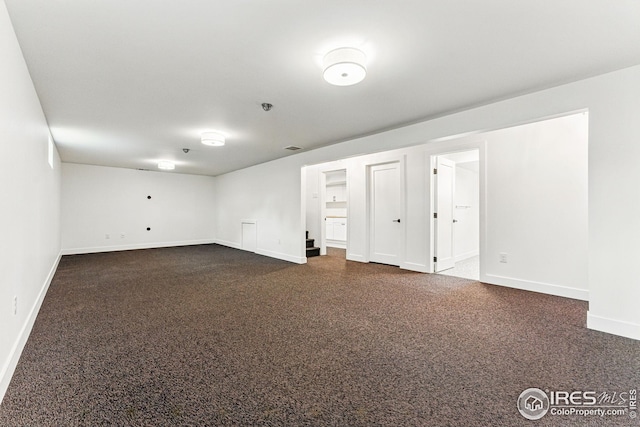 below grade area with baseboards, dark colored carpet, and visible vents