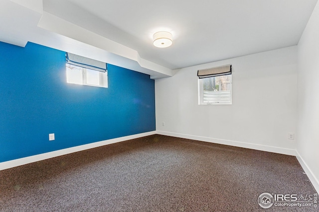 empty room with dark colored carpet and baseboards