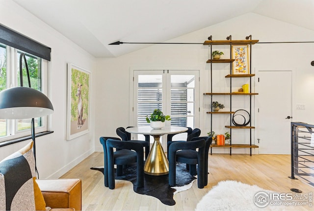 dining area featuring lofted ceiling and light wood finished floors