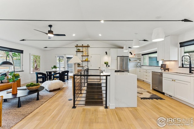 kitchen featuring appliances with stainless steel finishes, white cabinetry, open shelves, and a sink