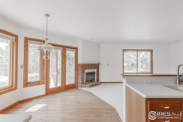 unfurnished living room featuring light wood-style flooring, a fireplace, a sink, baseboards, and visible vents