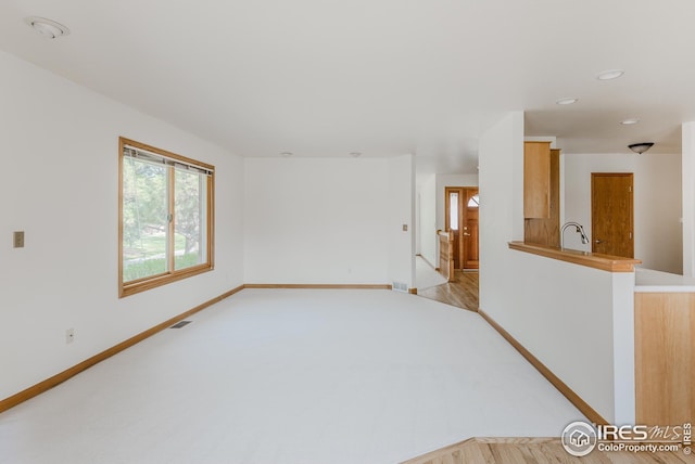 spare room featuring baseboards, recessed lighting, light carpet, and a sink