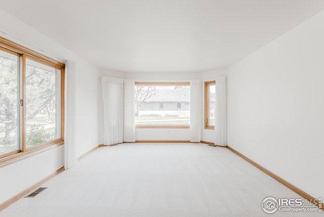 unfurnished room with visible vents, baseboards, and light carpet