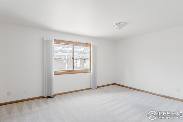 empty room featuring visible vents, light carpet, and baseboards